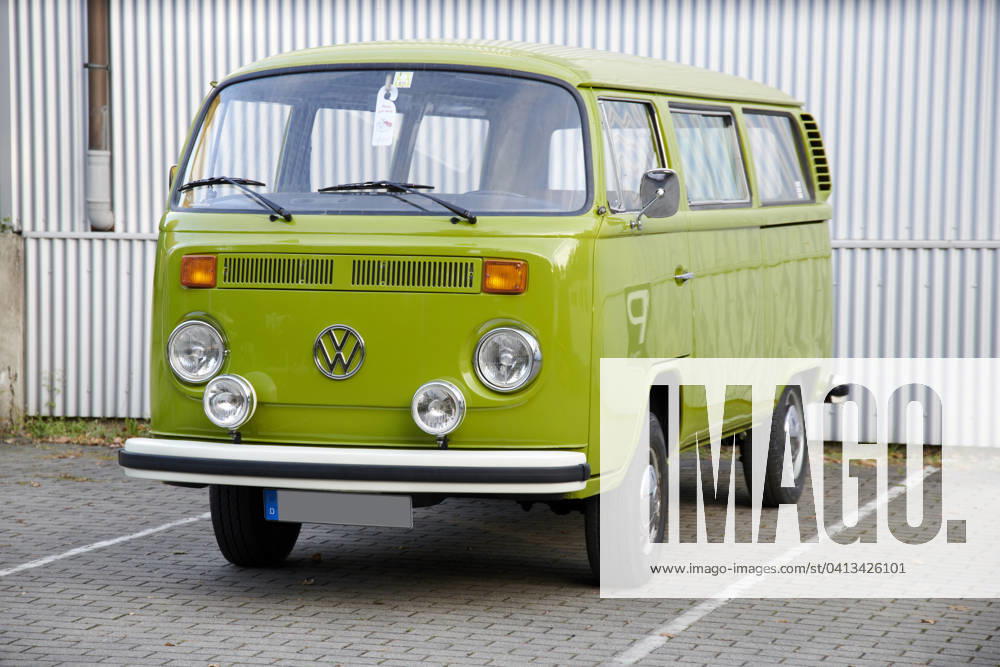 Oldtimer VW Bulli T2 Ein sehr gepflegter Grashuepfer gruener VW Bulli T2 steht auf einem eingezeichneten Parkplatz vor einer weissen Wellblechwand. Essen