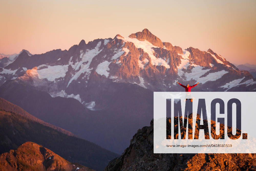 A hiker jumps off rocky cliff in North Cascades National Park. Glacier, Washington, United States CR_JDIP240227-1346428-01 ,model released, Symbolfoto