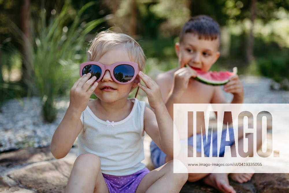 Little chidren sitting near lake and eating watermelon on hot sunny day during summer vacation. Little chidren sitting near a lake and eating watermelon on hot sunny day during summer vacation. model released