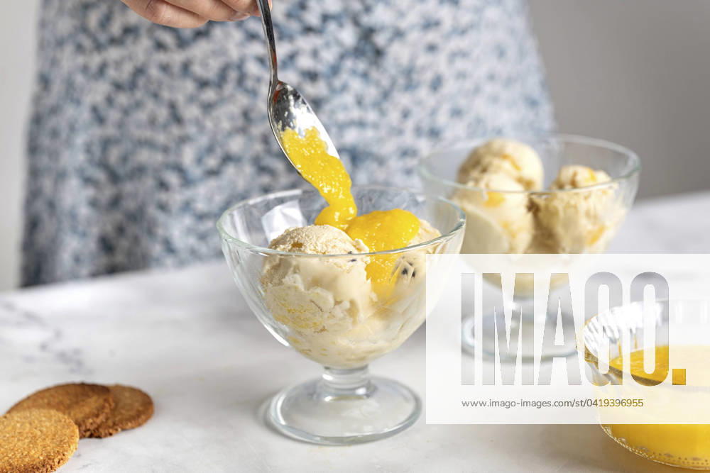 Woman putting fruit sauce on ice cream in bowl model released, Symbolfoto, TILF00070