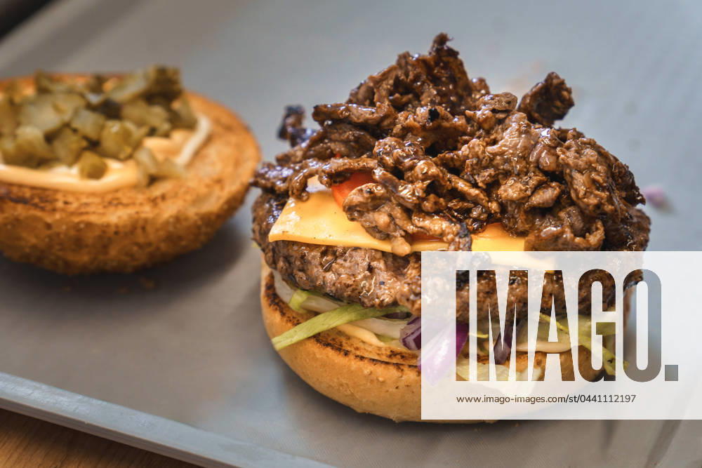 Zubereiteter Philly-Cheese-Burger auf einem Tablett in einem Imbiss mit frischem Rindfleisch, Tomate, Salat und geröstetem Hamburger Brötchen