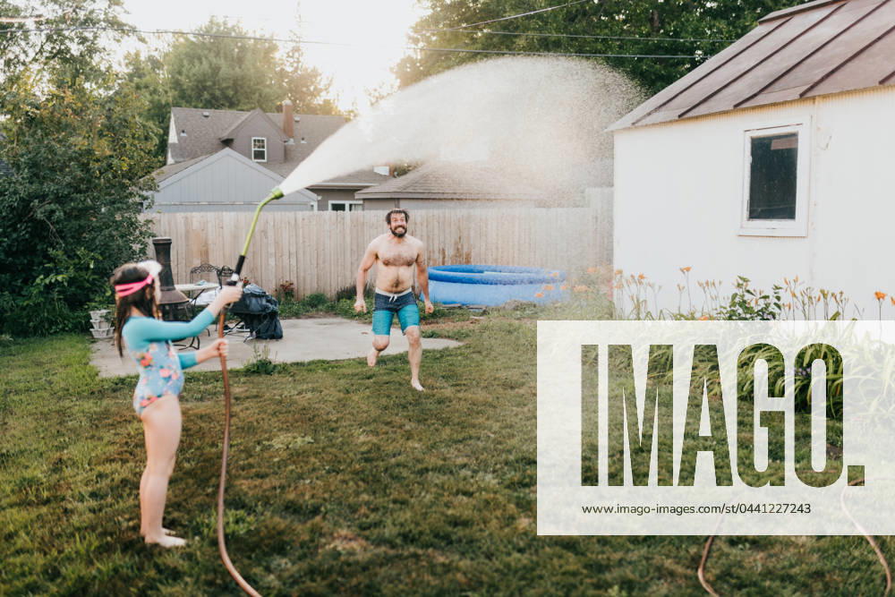 Young girl holds garden hose while dad runs through water Sioux Falls, South Dakota, United States CR_ASWE240317-1369123-01 ,model released, Symbolfoto ,property released