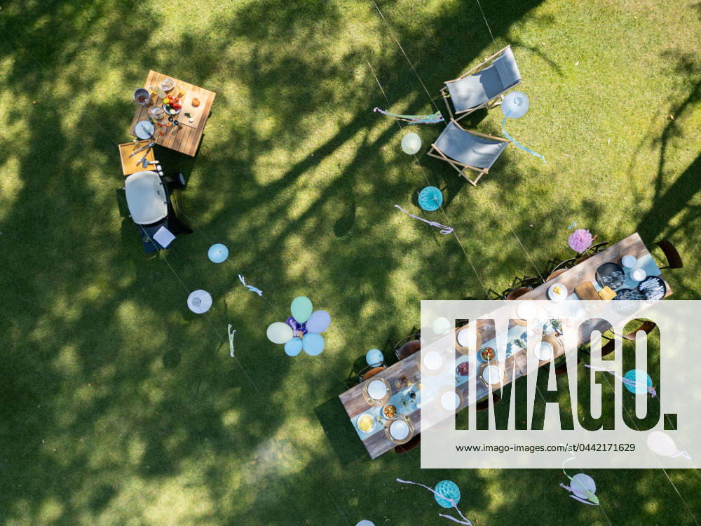 Top view of summer garden party in a beautiful garden. BBQ family gathering with a set table and colorful decorations. Top view of summer garden party in a beautiful garden. BBQ family gathering, with a set table and colorful decorations. model released