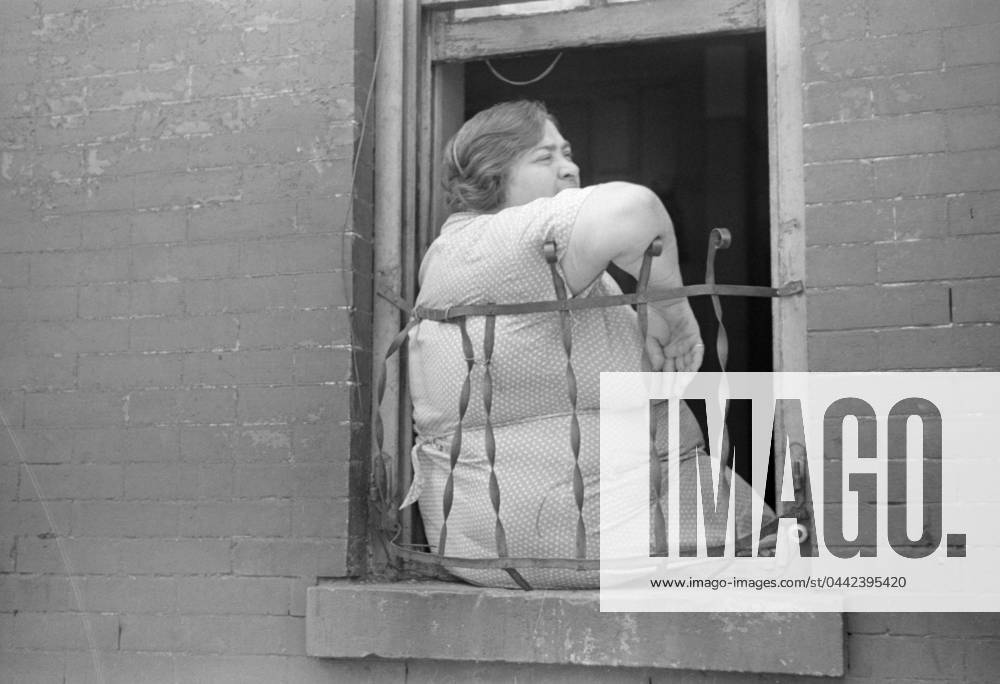EVANS: NEW YORK, 1938. A woman sitting in window of her apartment on 61st Street between 1st and 3rd Avenues, New York, New York. Photograph by Walker Evans, 1938.
