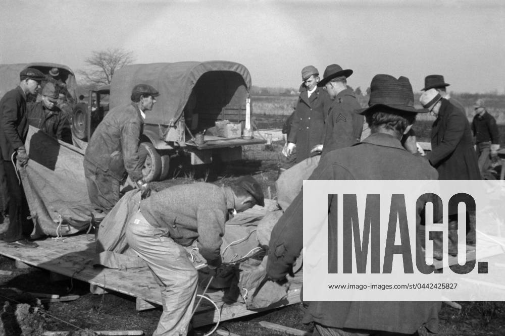 ARKANSAS: FLOOD CAMP, 1937. Setting up a tent in a camp for white flood refugees at Forrest City, Arkansas. Photograph by Walker Evans, February 1937.