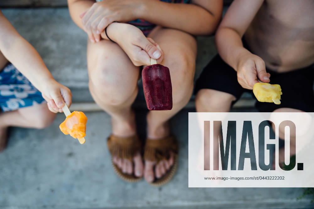 IMAGO Creative, Jahreszeit Sommer, Hitze Overhead view of three kids with popsicles sitting outside United States, North Dakota, Bismarck CR_KIFR240402-1377366-01 ,model released, Symbolfoto