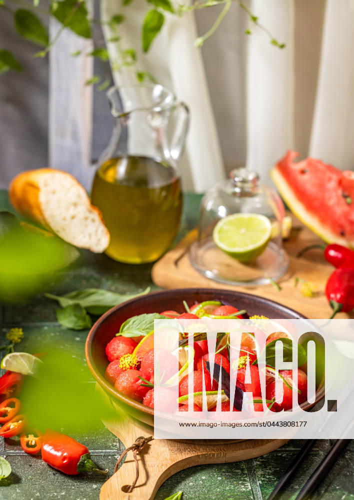 Spicy salad of fresh watermelon balls with basil, lime, rosemary and fennel, topping with olive oil Spicy salad of fresh watermelon balls with basil, lime, rosemary and fennel, topping with olive oil on dark green table surface with sunny light