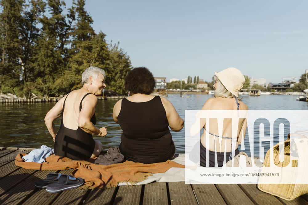 Rear view of female senior friends having fun while sitting on houseboat near lake Germany, Berlin, model released, property released