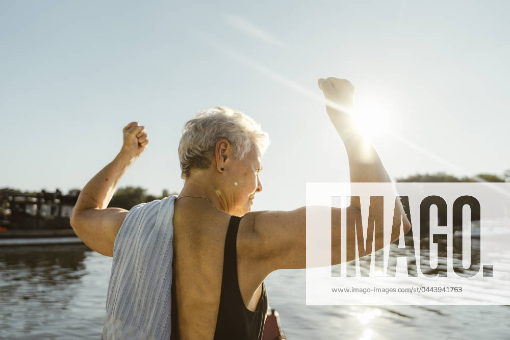 Senior woman flexing muscles on houseboat during vacation at sunny day Germany, Berlin, model released, property released