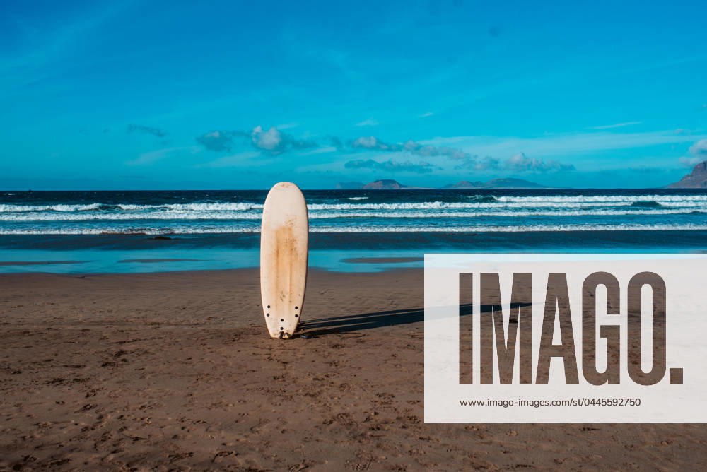 Surfboard in sand on a sunny beach during sunset. Surfboard stucked in sand on a sunny beach during sunset. model released