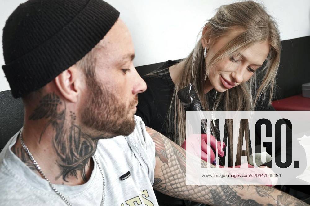 Tätowiererin Jessica Wierzchnicki (rechts) arbeitet am Samstag, 20.04.2024 in der Traber-Kneipe-Sportsbar an der Hansemannstraße in Gelsenkirchen am Tattoo von Benamin Reinartz. Im großen Tattoo-Marathon stechen Tätowierer kleinere Motive für einen guten Zweck - Tätowiererin Anke ist schwerkrank und finanziell angeschlagen. Deutschland NRW Gelsenkirchen