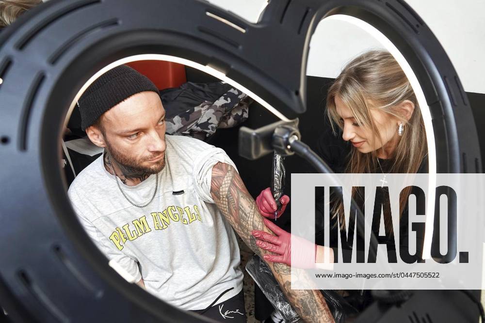 Tätowiererin Jessica Wierzchnicki (rechts) arbeitet am Samstag, 20.04.2024 in der Traber-Kneipe-Sportsbar an der Hansemannstraße in Gelsenkirchen am Tattoo von Benamin Reinartz. Im großen Tattoo-Marathon stechen Tätowierer kleinere Motive für einen guten Zweck - Tätowiererin Anke ist schwerkrank und finanziell angeschlagen. Deutschland NRW Gelsenkirchen