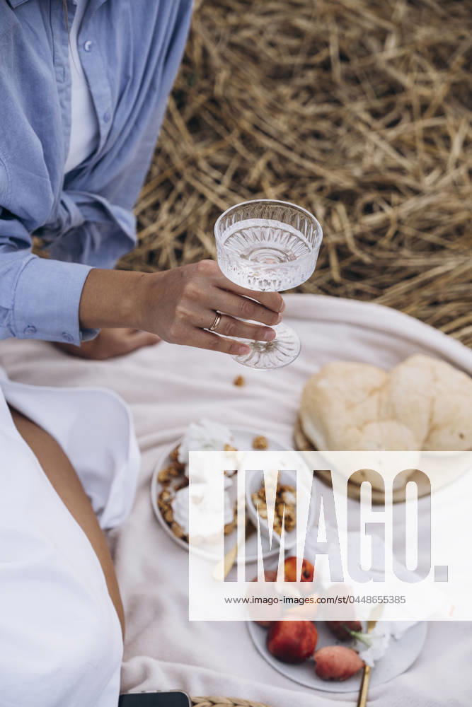 Hand of woman holding glass of water with snacks on picnic blanket model released, Symbolfoto, KANF00061