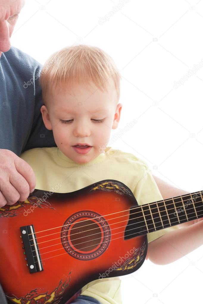 Grandfather teaching grandson play on acoustic guitar. Over white background model released