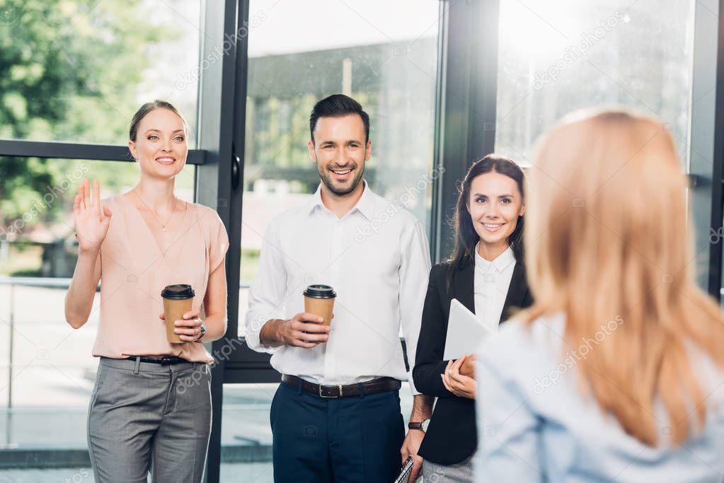 Smiling colleagues looking at businesswoman during coffee break in office model released