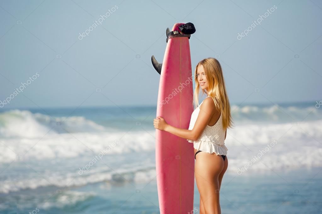 A beautiful surfer girl at the beach with her surfboard model released