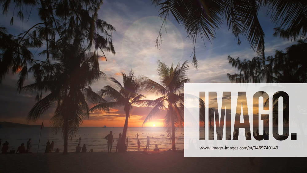 Sunset on beach with people and palms Silhouetted people and palms near sea. Sunset at tropical White beach, Boracay island, Philippines