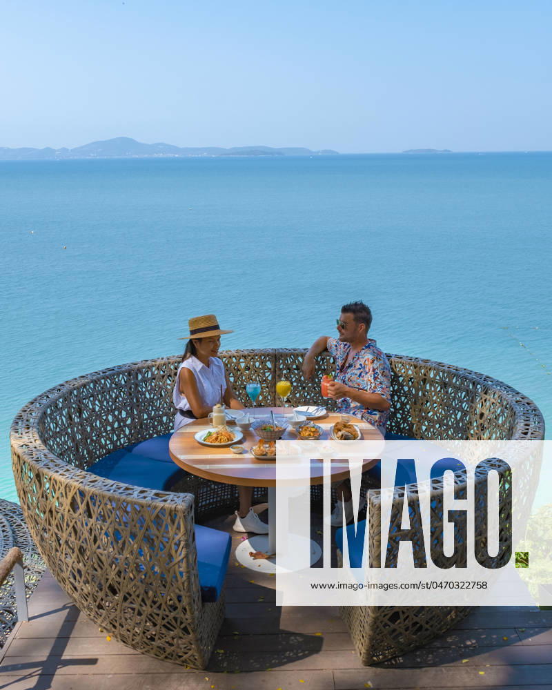 Couple having lunch at an restaurant looking out over the ocean of Pattaya Thailand couple having lunch at a restaurant looking out over the ocean of Pattaya Thailand, man and woman having dinner in a restaurant by the ocean in Pattaya during summer