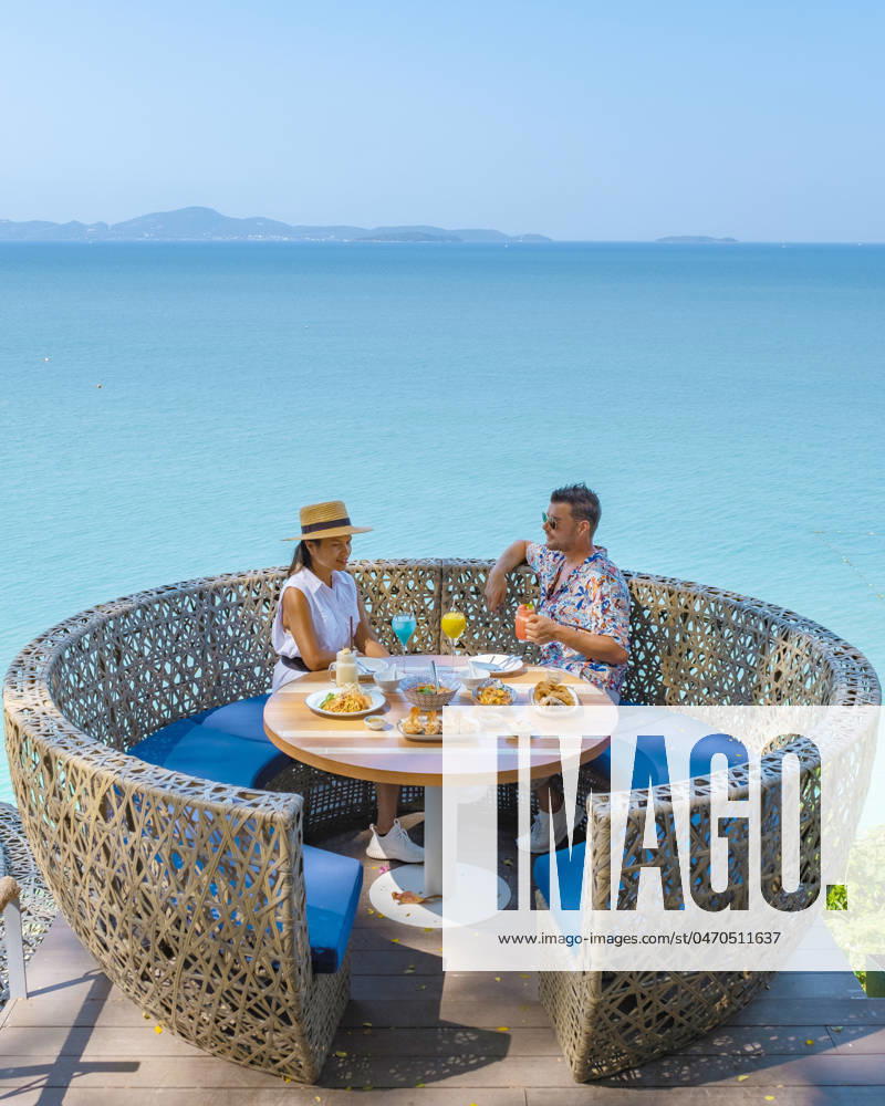 Couple having lunch at an restaurant looking out over the ocean of Pattaya Thailand couple having lunch at a restaurant looking out over the ocean of Pattaya Thailand, man and woman having dinner in a restaurant by the ocean in Pattaya during summer