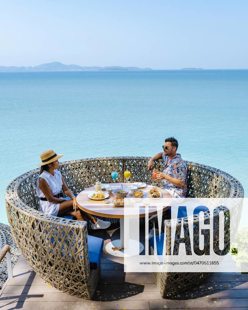 Couple having lunch at an restaurant looking out over the ocean of Pattaya Thailand, man and woman having dinner in restaurant by the ocean in Pattaya couple having lunch at a restaurant looking out over the ocean of Pattaya Thailand, man and woman having dinner in a restaurant by the ocean in Pattaya.