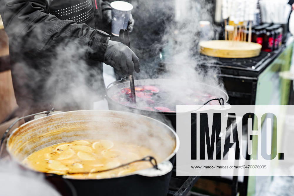Hot mulled wine on a street food market Beverages fruits and berries hot mulled wine in pots with steam in street food market. Colorful hot sweet drinks at fair festival outdoors closeup