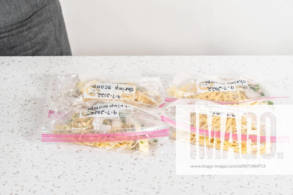 IMAGO Creative, Food, Trend, Meal Prep Frozen shrimp scampi meal prep Packaging homemade frozen shrimp scampi meal prep into plastic resealable bags.