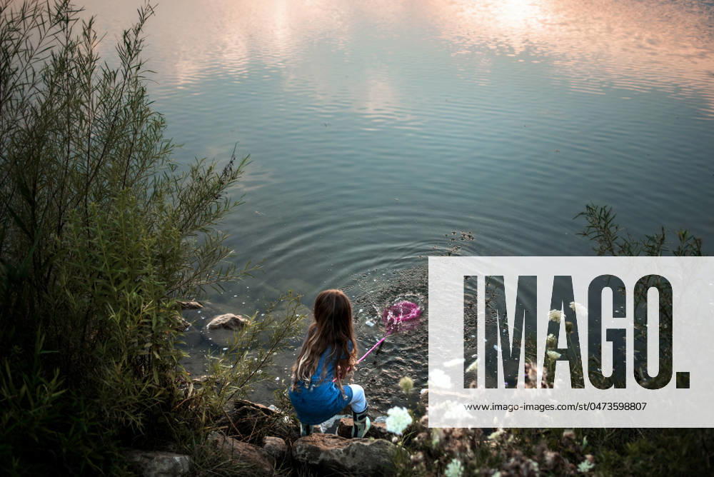 IMAGO Creative, Jahreszeit Sommer, Sommerferien Young girl splashing water in lake at sunset Wooster, Ohio, United States CR_JOKU240507CB-1422584-01 ,model released, Symbolfoto