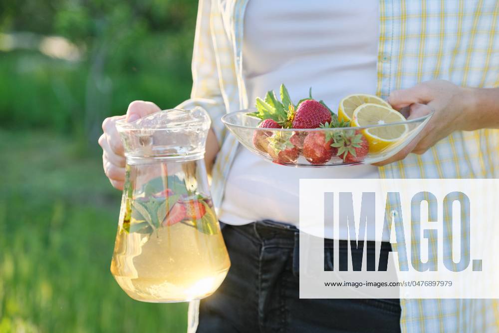 Spring summer refreshments, woman in nature holding jar of strawberry mint and lemon Spring summer refreshments, woman in nature holding jar of strawberry mint and lemon.