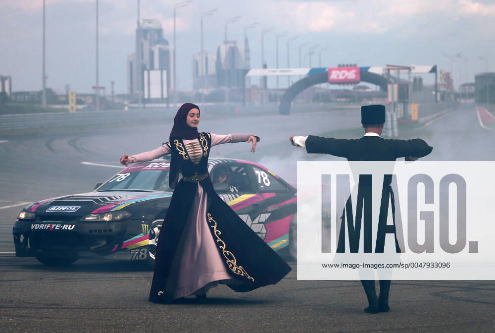KW34 GROZNY, RUSSIA - AUGUST 23, 2020: Dancers in national costumes perform by a racing car during the first race of the 2020 Russian Drift Series Yug at Fort Grozny Autodrom. Yelena Afonina TASS TS0E46D3