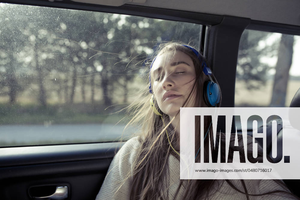 Young woman with eyes closed listening to music through headphones in car model released, Symbolfoto, PNEF02983