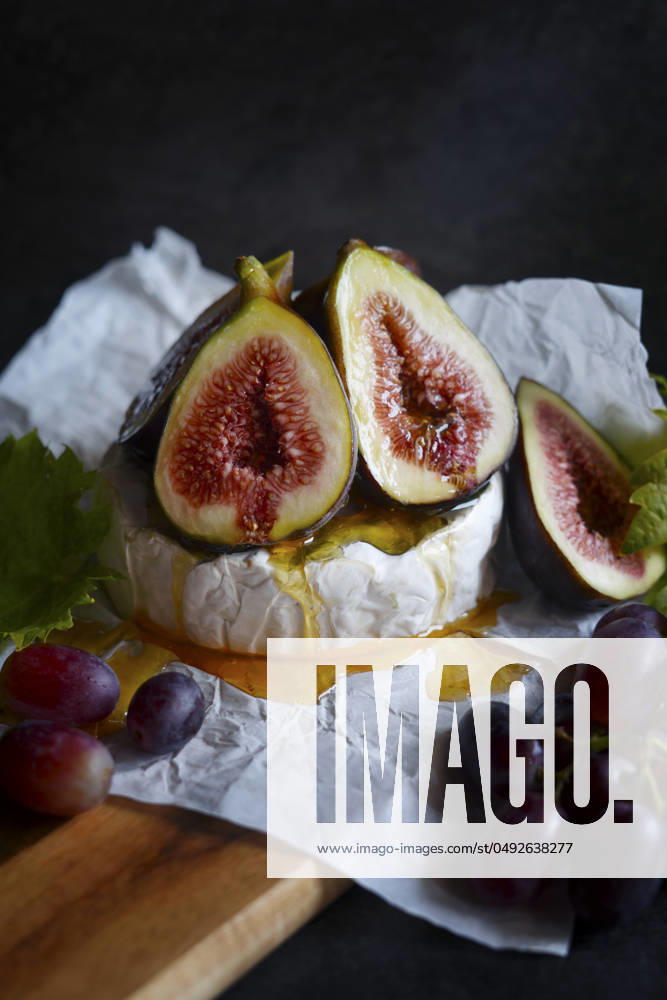 Brie cheese served with figs, honey and grapes, close up. Brie cheese served with figs, honey and grapes, close up.