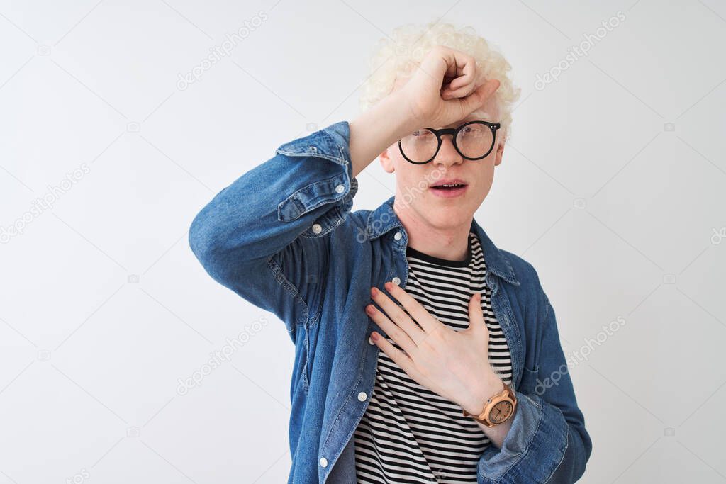 Young albino blond man wearing denim shirt and glasses over isolated white background Touching forehead for illness and fever, flu and cold, virus sick model released