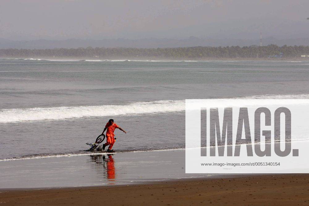 Rettungskraft zieht ein Fahrrad aus dem Meer nach dem Tsunami in Pangandaran auf Java -