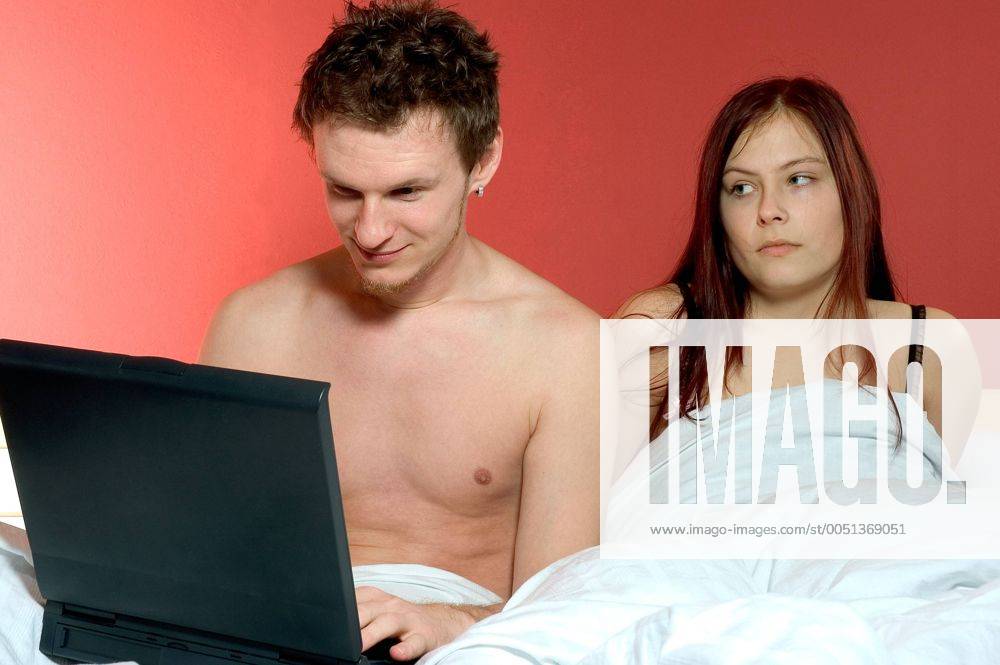 Frust im Bett - Junge Frau ist genervt vom Freund mit Notebook