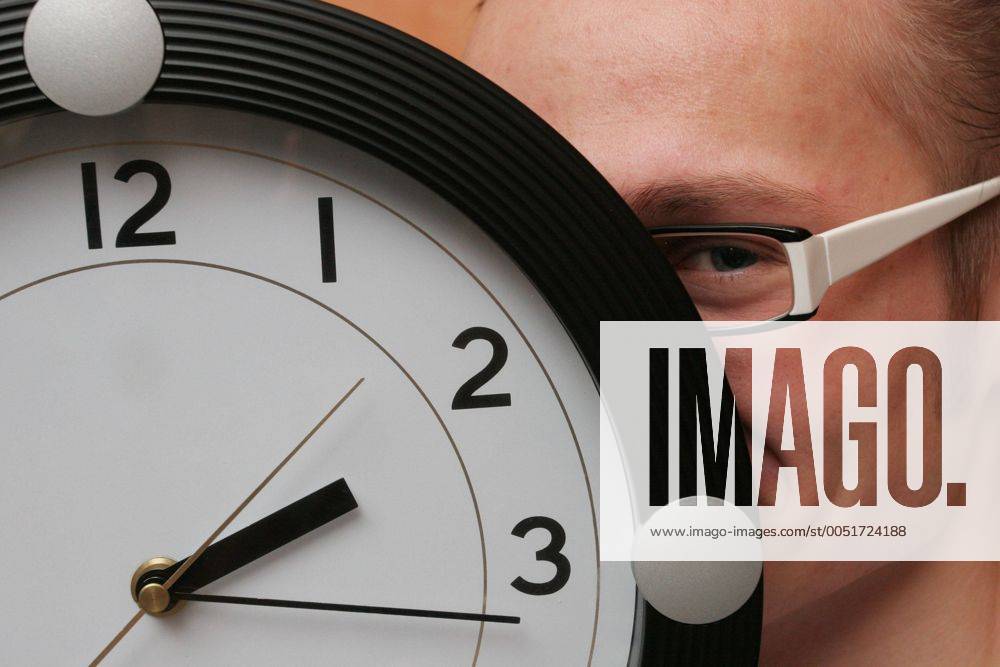Junger Mann versteckt sein Gesicht hinter einer Uhr