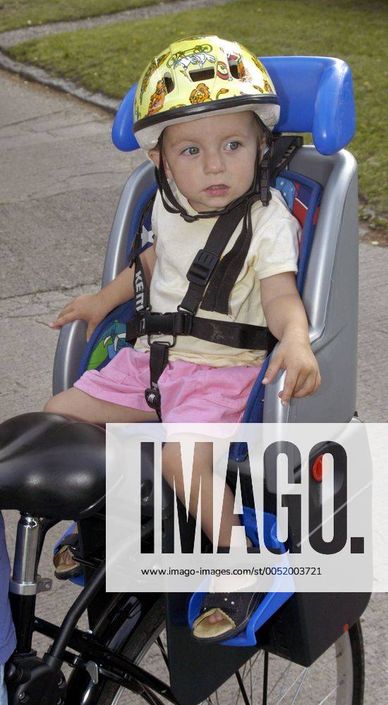Kleines Mädchen sitzt mit Sturzhelm auf einem Kettler-Fahrradsitz