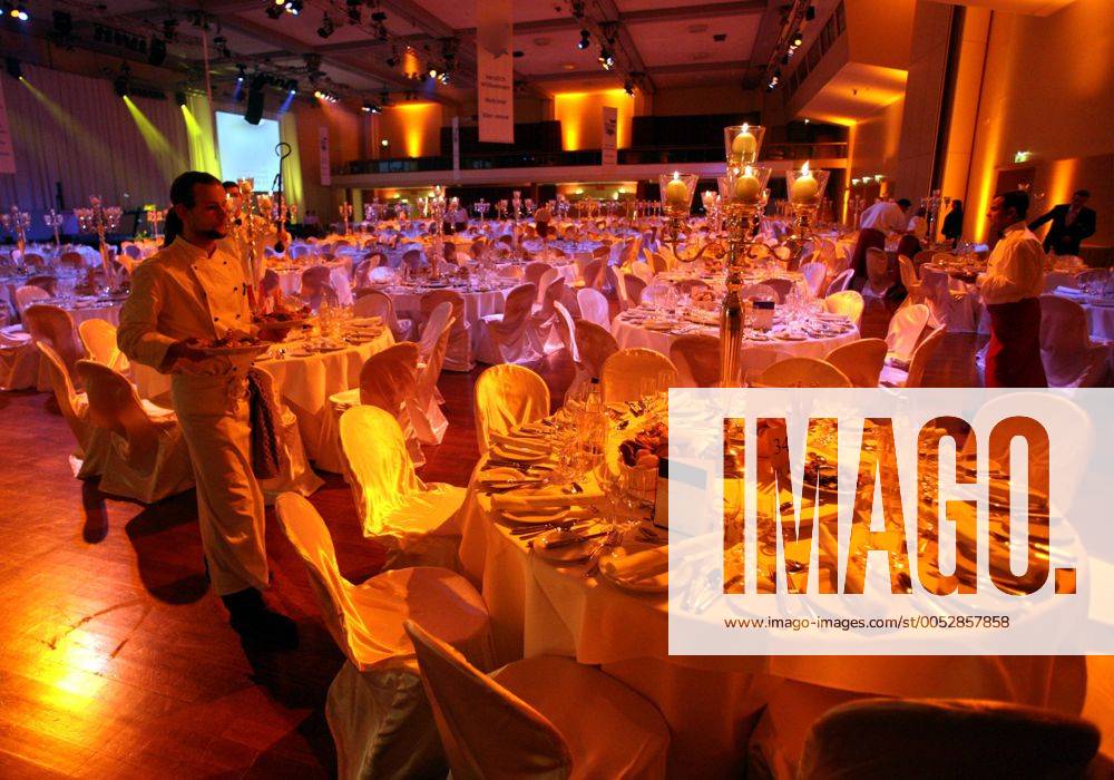 Kellner deckt Tische für ein festliches Dinner ein im Estrel Convention Center in Berlin