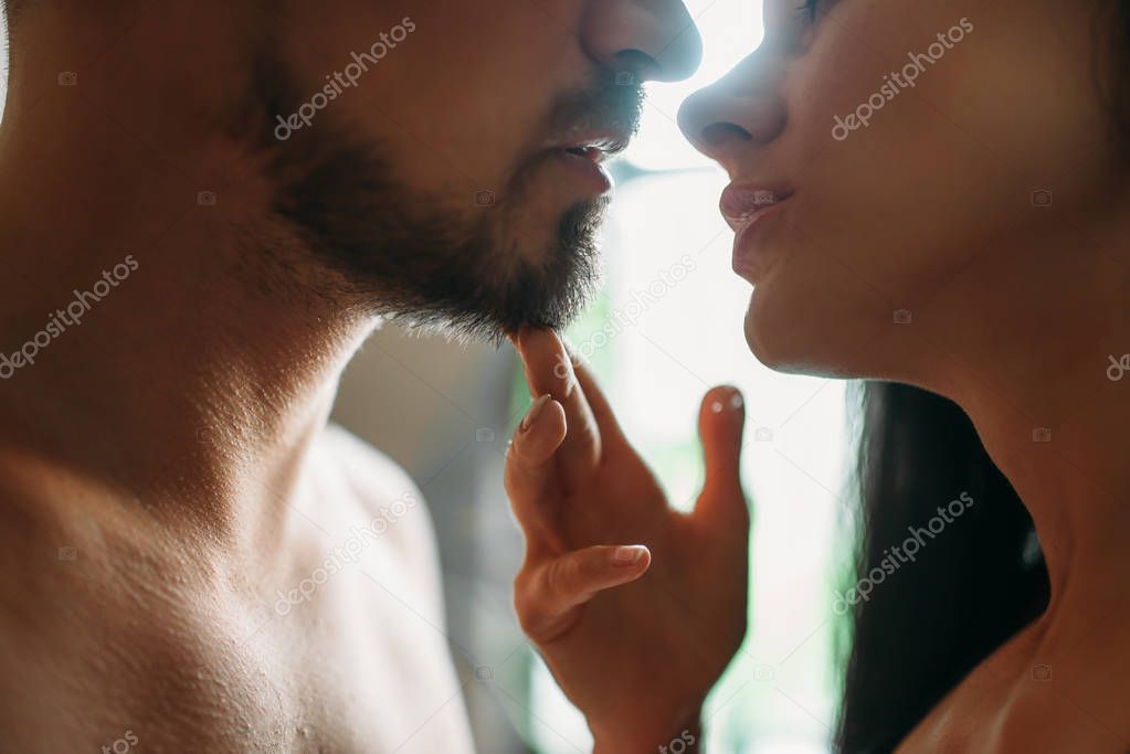 Man and woman kissing against a window with sunlight, erotica. Erotic scene, sexual relationship model released