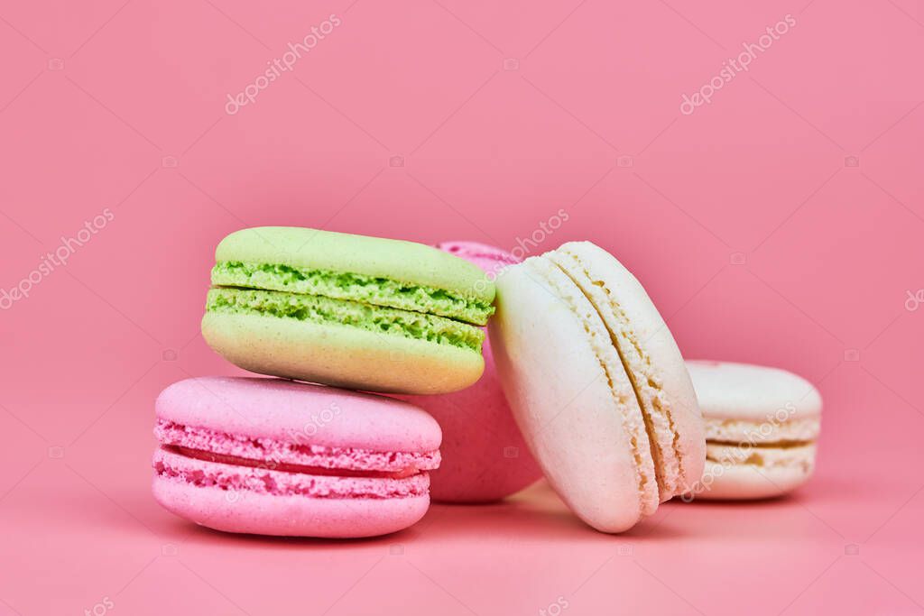Macaroons on pink background. Colorful small cookie from ground almonds and coconut. Popular confectionery. Tasty snack food for take away, copy space