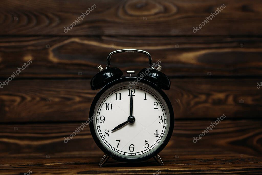 Clock on a wooden background. The clock shows the time of eight o'clock in the afternoon. The clock shows the time of eight o'clock in the morning. An image of a retro clock showing 08:00 pm/am. Copy space