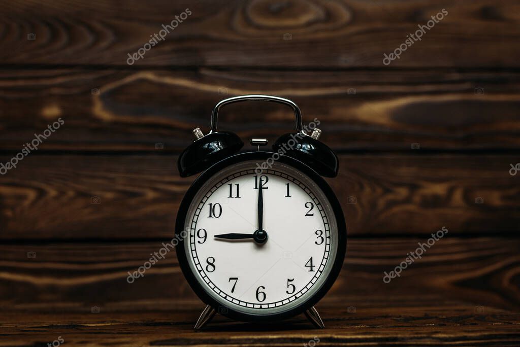 Clock on a wooden background. The clock shows the time of nine o'clock in the afternoon. The clock shows the time of nine o'clock in the morning. An image of a retro clock showing 09:00 pm/am. Copy space