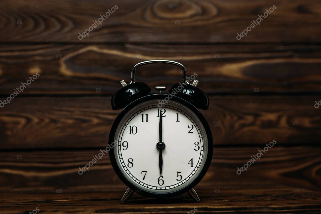 Clock on a wooden background. The clock shows the time of six o'clock in the afternoon. The clock shows the time six o'clock in the morning. An image of a retro clock showing 06:00 pm/am. Copy space
