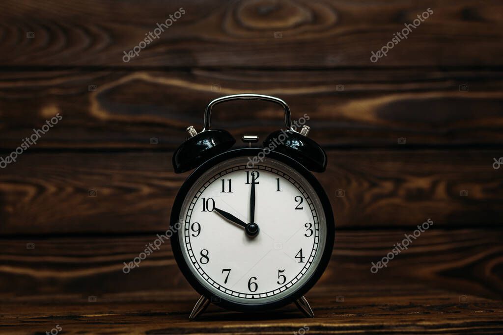Clock on a wooden background. The clock shows the time of ten o'clock in the afternoon. Clock showing the time of ten o'clock in the morning. An image of a retro clock showing 10:00 pm/am. Copy space