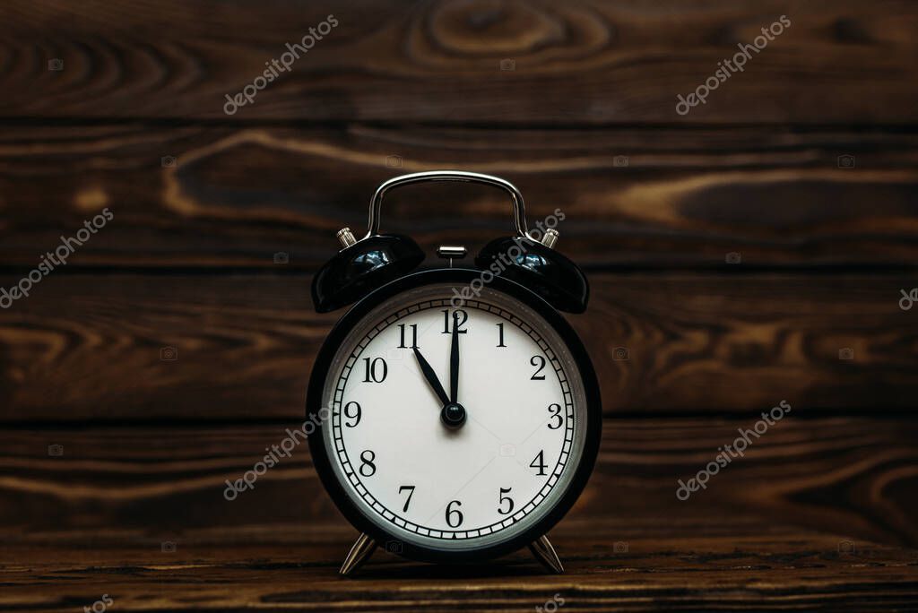 Clock on a wooden background. The clock shows the time of eleven o'clock in the afternoon. The clock shows the time of eleven o'clock in the morning. An image of a retro clock showing 11:00 pm/am. Copy space