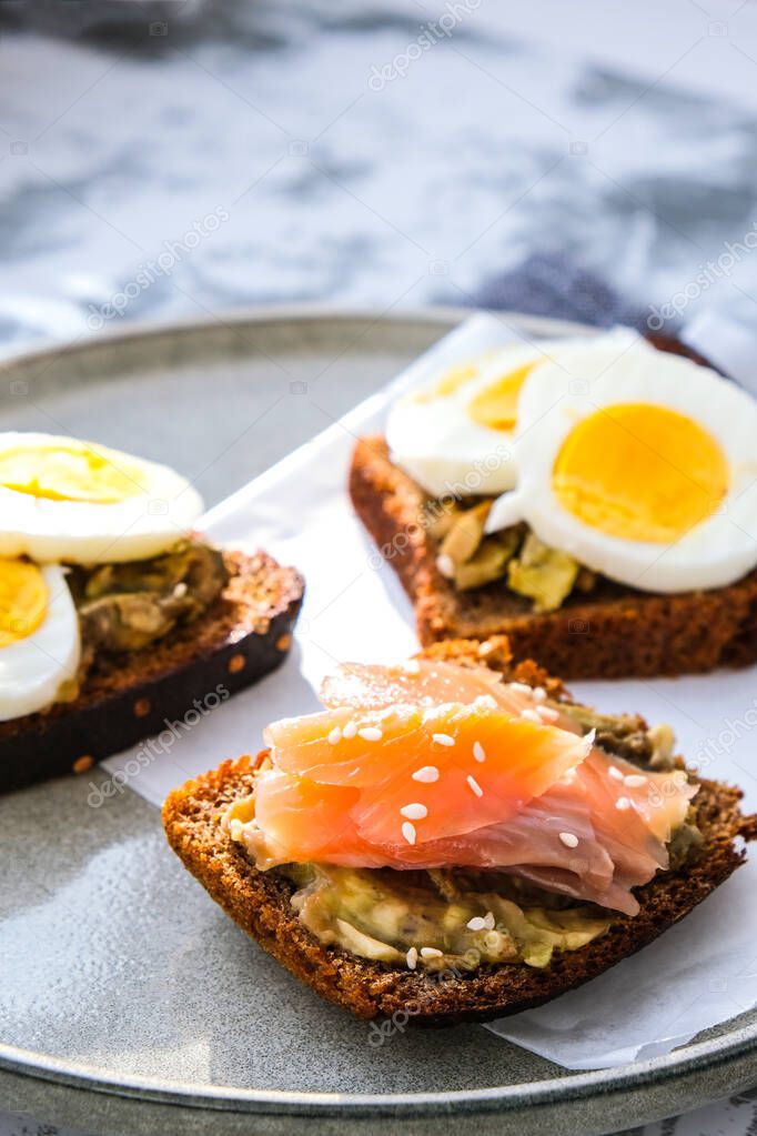 Toasted breads with boiled eggs, avocado and salmon. Guacamole sandwiches. Healthy breakfast. Sesame seeds. Vegetarian healthy eating. Diet. Snack Selective focus, close up