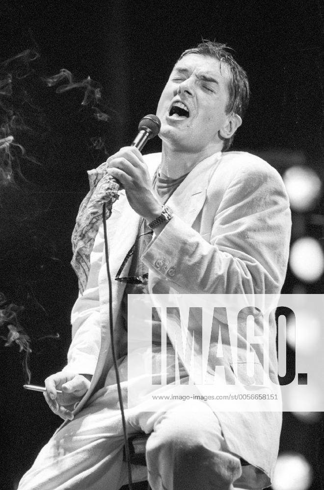Falco (Sänger, Musiker) 10 86 dar Falco bei einem Konzert im Oktober 1986 Mann Gesang Musik Pop Rock Künstler Österreicher Österreich österreichisch österreichischer Johann Hölzel Bühne Auftritt Show seriös sitzend Hocker Barhocker singend Mikrofon Mikro Hemd Jackett Sakko Zigarette haltend Augen geschlossen dunkelhaarig Gelfrisur zurückgekämmt halb Singer Music Musician Performance Stage hoch sw