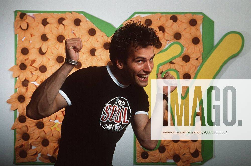 Holger Speckhahn (VJ bei MTV) 04 97 her Mann TV Fernsehen Moderation Musik VJ Videojockey MTV dunkelhaarig leger T-Shirt Logo Studio dekoration Kulisse stehend halb quer posierend gestikulierend lächelnd