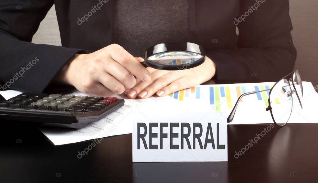 Close up Business woman using calculator and charts do math finance on the wooden desk in office and business working background with text REFERRAL