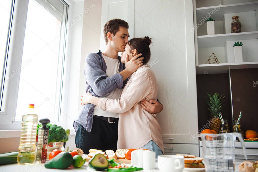 Couple hugging in the kitchen after they finished preparing breakfast. Man kissing woman on the forehead. Healthy lifestyle. Vegetarian healthy food. Healthy model released