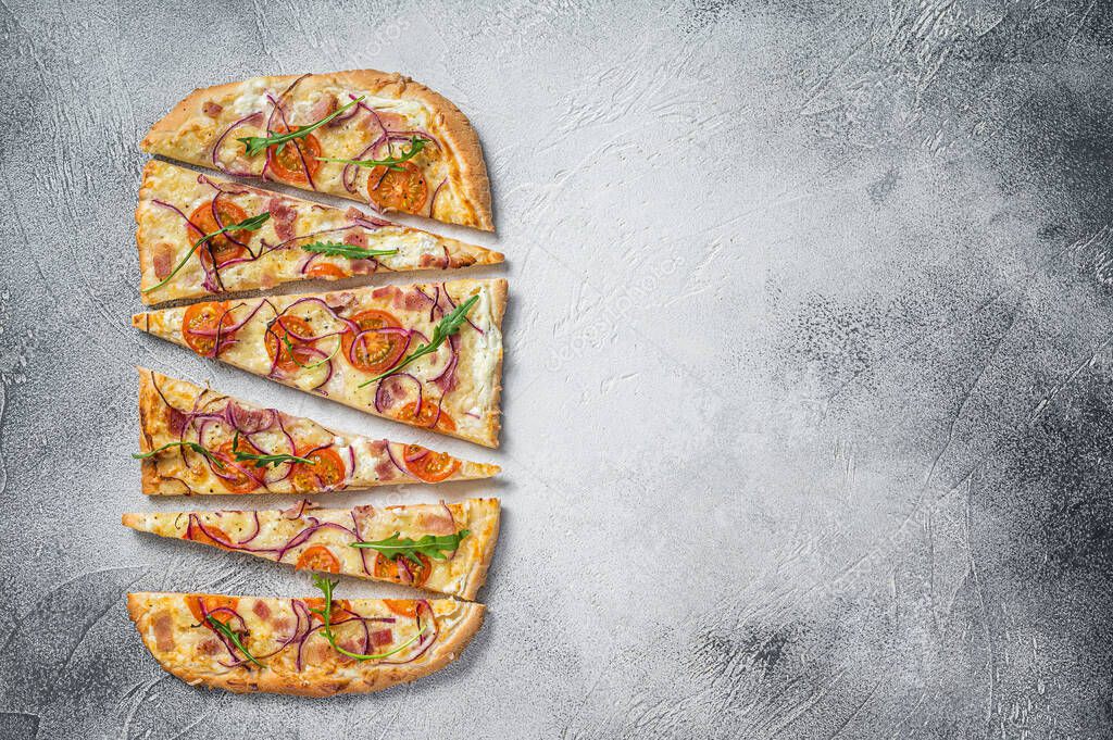 French tarte flambee with cream cheese, bacon, tomato and onions. Flammkuchen from Alsace region. White background. Top view. Copy space.